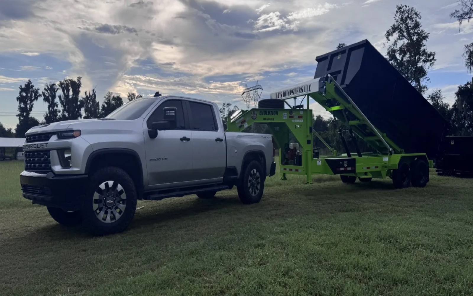 DJ's Dumpsters truck and lime-green roll-off trailer carrying a black container