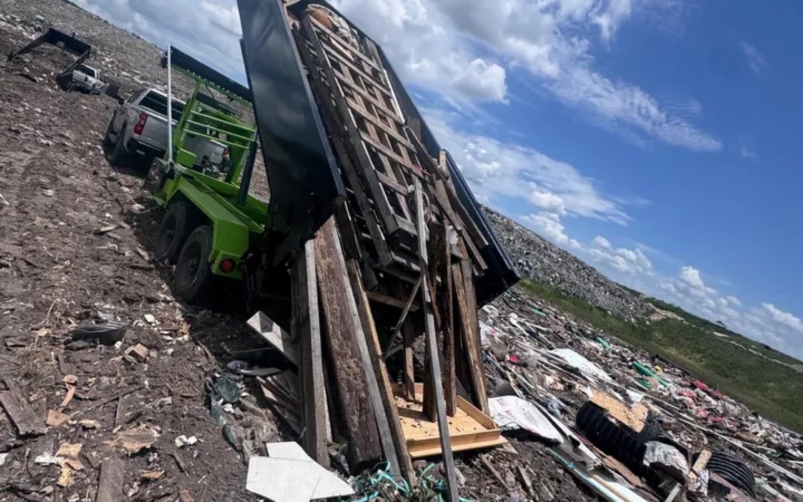 DJ's Dumpsters roll-off equipment unloading approved wood debris at a disposal site