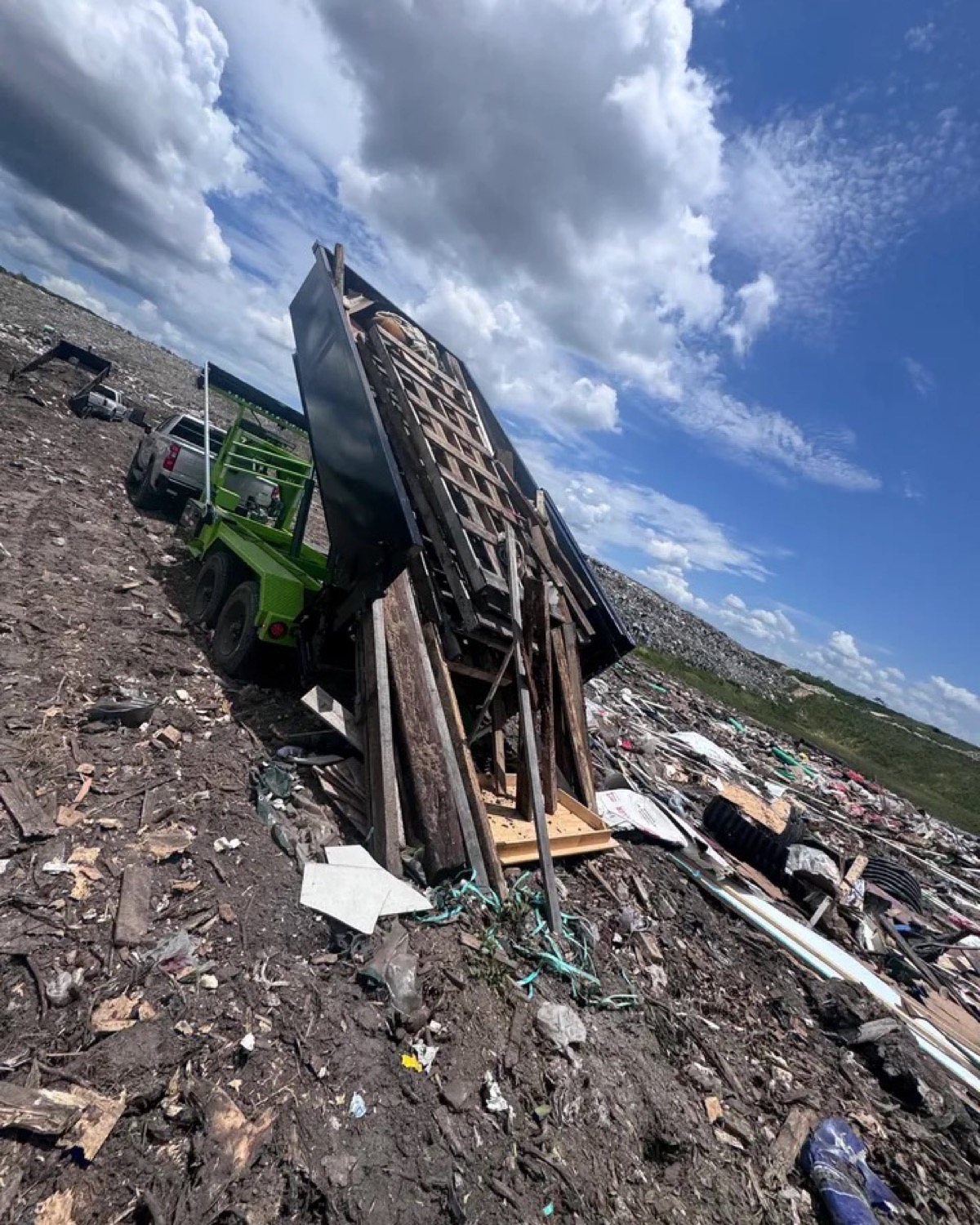 Wood debris sliding from a black roll-off dumpster during disposal